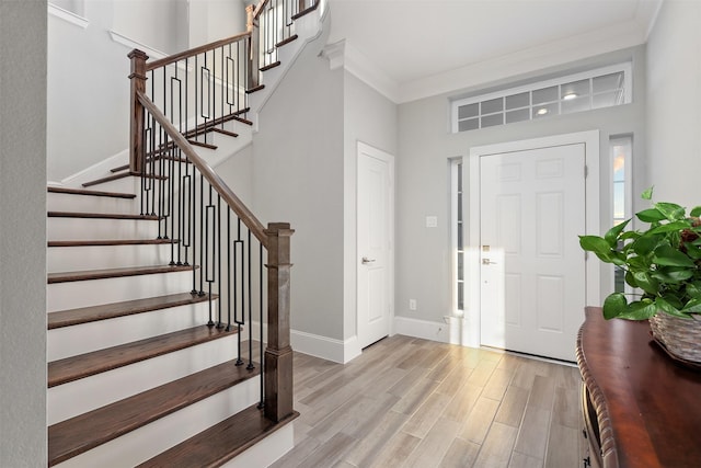 entryway featuring ornamental molding, baseboards, stairway, and light wood-type flooring