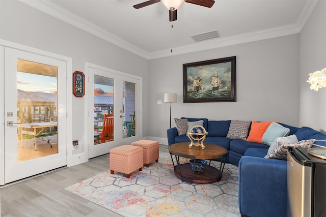 living area featuring ornamental molding, visible vents, ceiling fan, and wood finished floors