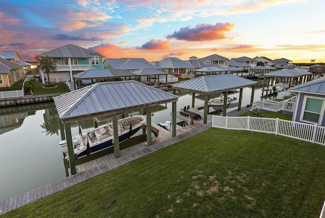 dock area featuring boat lift, a residential view, a water view, and a yard