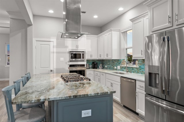 kitchen featuring a sink, tasteful backsplash, a kitchen breakfast bar, stainless steel appliances, and island range hood