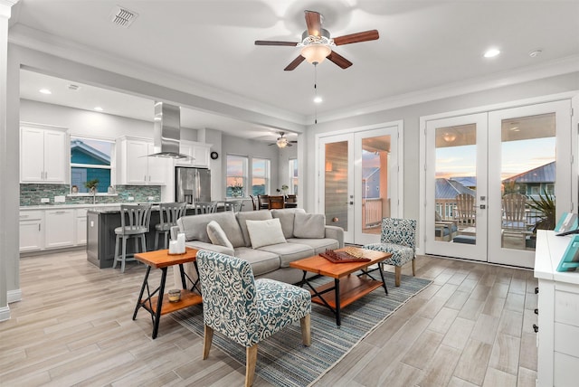 living area featuring wood tiled floor, visible vents, french doors, and a ceiling fan