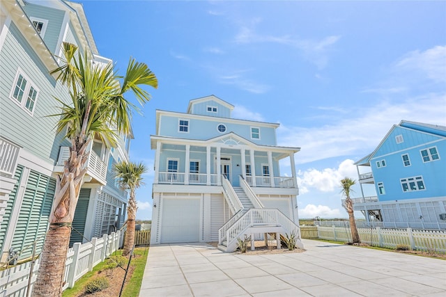 11367 Beachside Dr, Galveston, TX 77554 - coastal inspired home featuring a porch, a garage, fence, concrete driveway, and stairs