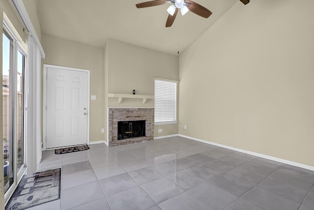 unfurnished living room featuring a ceiling fan, plenty of natural light, a brick fireplace, and tile patterned flooring