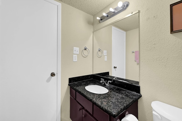 half bath with a textured ceiling, toilet, and vanity