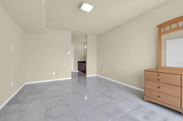 unfurnished room with baseboards, a textured ceiling, and tile patterned flooring