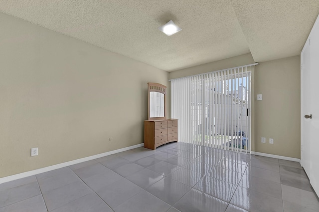 tiled empty room with baseboards and a textured ceiling