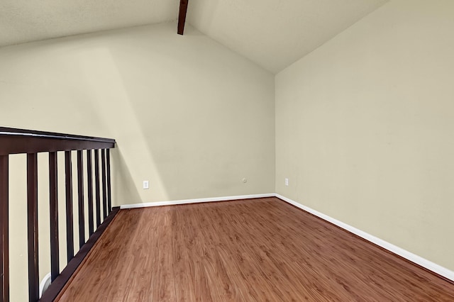 unfurnished room with baseboards, vaulted ceiling with beams, and wood finished floors