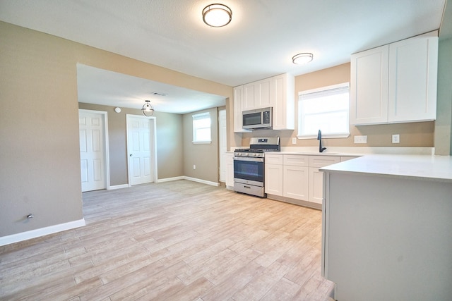 12234 Dumas St, Houston, TX 77034 - kitchen with stainless steel appliances, white cabinets, light countertops, light wood-type flooring, and baseboards