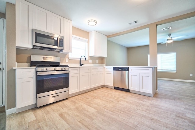 12234 Dumas St, Houston, TX 77034 - kitchen featuring stainless steel appliances, light countertops, light wood-style flooring, white cabinetry, and a ceiling fan