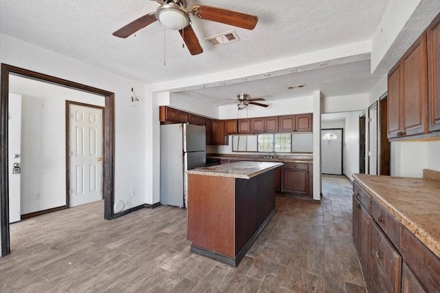 5401 Bayou Dr, Dickinson, TX 77539 - kitchen featuring visible vents, ceiling fan, wood finished floors, and freestanding refrigerator