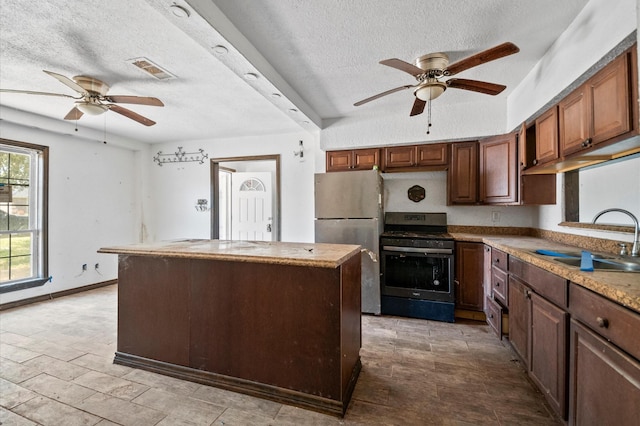 5401 Bayou Dr, Dickinson, TX 77539 - kitchen with a sink, a kitchen island, a ceiling fan, freestanding refrigerator, and stainless steel gas range oven
