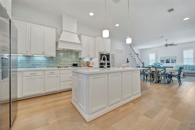 4 Caravelle Ct, Galveston, TX 77554 - kitchen featuring custom exhaust hood, open floor plan, light countertops, white cabinetry, and stainless steel appliances