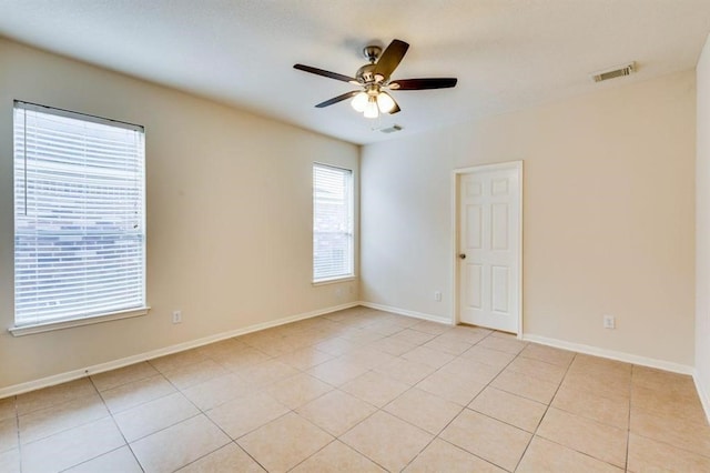 empty room with a ceiling fan, light tile patterned floors, baseboards, and visible vents