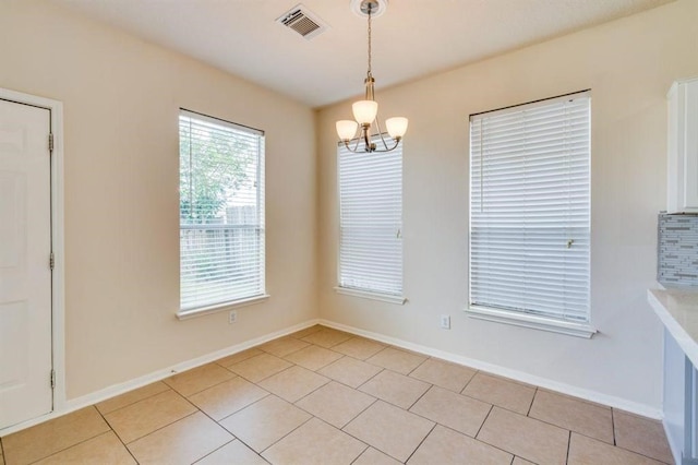 unfurnished dining area with light tile patterned floors, baseboards, visible vents, and a notable chandelier