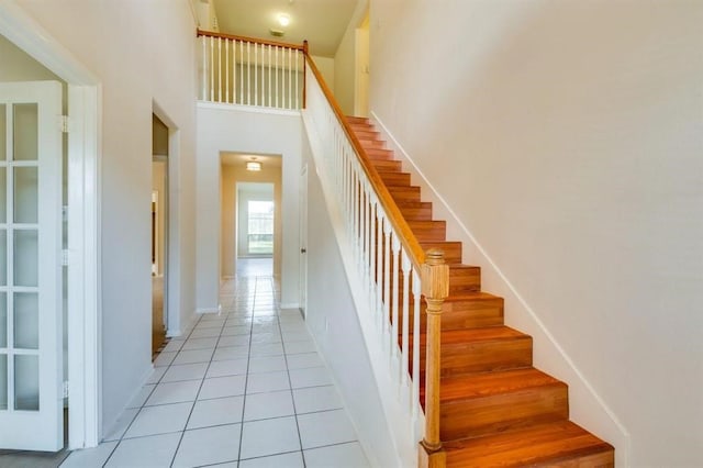 staircase with a high ceiling, tile patterned floors, and baseboards