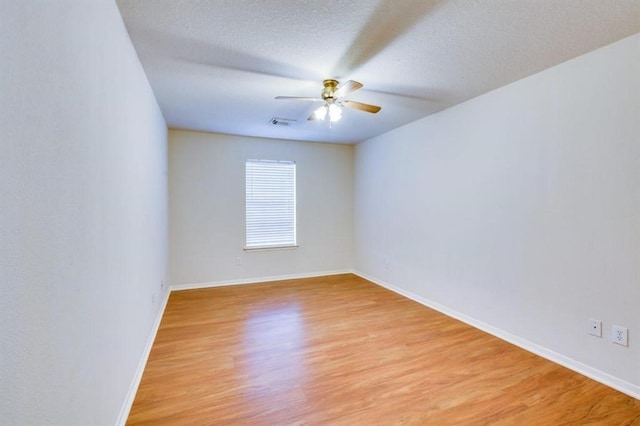 unfurnished room with light wood-style flooring, baseboards, a textured ceiling, visible vents, and a ceiling fan