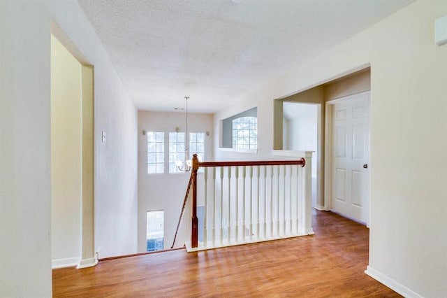 unfurnished room with baseboards, an inviting chandelier, wood finished floors, and a textured ceiling