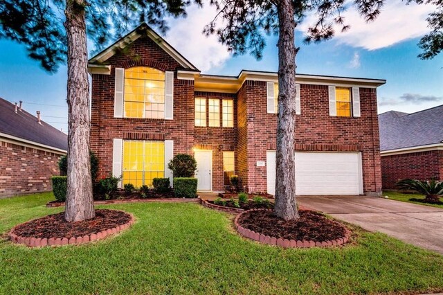 view of front of house featuring driveway, brick siding, a garage, and a front yard