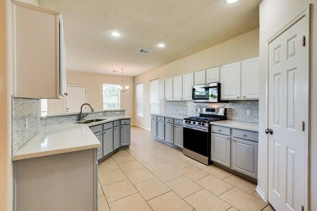 kitchen with visible vents, a peninsula, appliances with stainless steel finishes, a sink, and gray cabinets