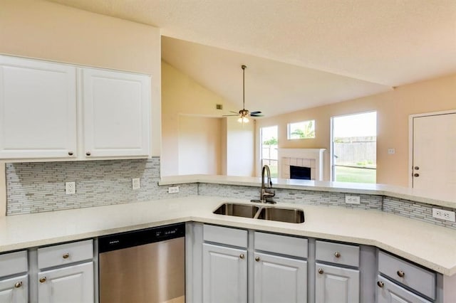 kitchen with vaulted ceiling, a sink, tasteful backsplash, stainless steel dishwasher, and ceiling fan
