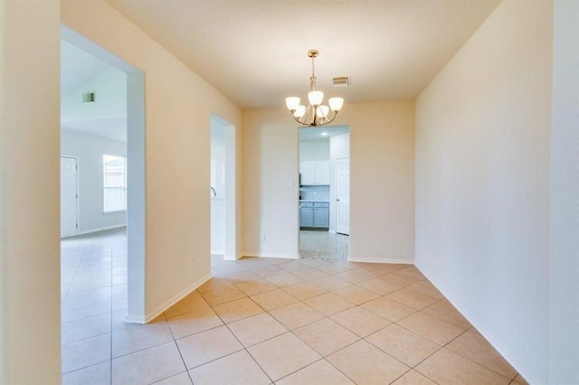 spare room with light tile patterned flooring, baseboards, a notable chandelier, and visible vents