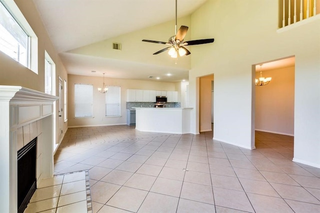 unfurnished living room with lofted ceiling, light tile patterned floors, ceiling fan with notable chandelier, visible vents, and a fireplace