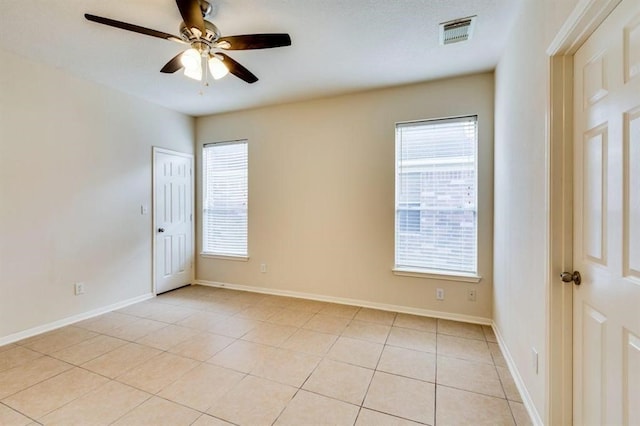 unfurnished room with light tile patterned flooring, baseboards, ceiling fan, and visible vents