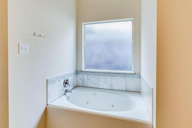 bathroom with a tub with jets and a healthy amount of sunlight