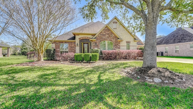 4210 Wentworth Dr, Fulshear, TX 77441 - french country home featuring brick siding, a front yard, central air condition unit, and roof with shingles