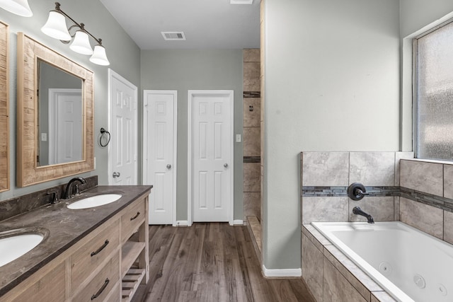 4810 Legends Bay Dr, Baytown, TX 77523 - bathroom with double vanity, a jetted tub, visible vents, wood finished floors, and a sink
