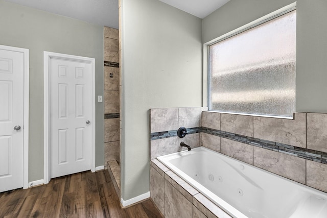 4810 Legends Bay Dr, Baytown, TX 77523 - bathroom featuring a tub with jets, baseboards, and wood finished floors