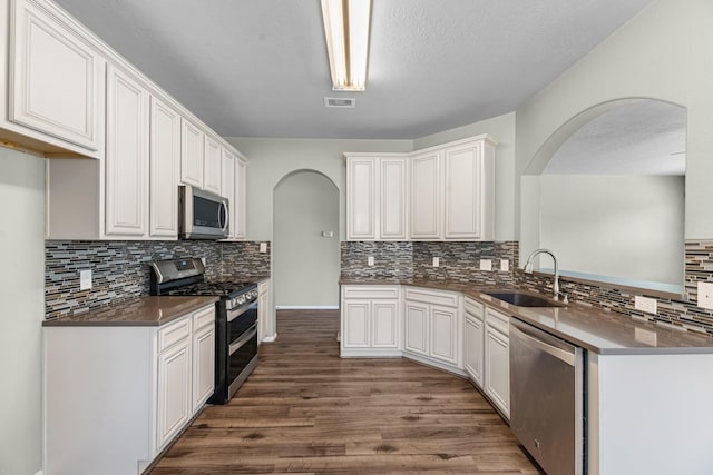 4810 Legends Bay Dr, Baytown, TX 77523 - kitchen with a sink, appliances with stainless steel finishes, arched walkways, and dark wood-type flooring