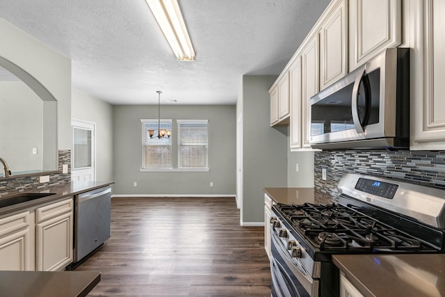 4810 Legends Bay Dr, Baytown, TX 77523 - kitchen featuring dark countertops, appliances with stainless steel finishes, a sink, arched walkways, and a chandelier