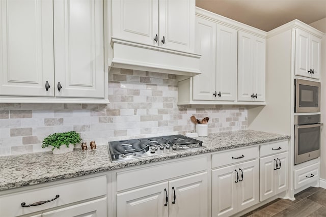 20207 Desert Foal Dr, Tomball, TX 77377 - kitchen with appliances with stainless steel finishes, white cabinetry, decorative backsplash, and light stone counters