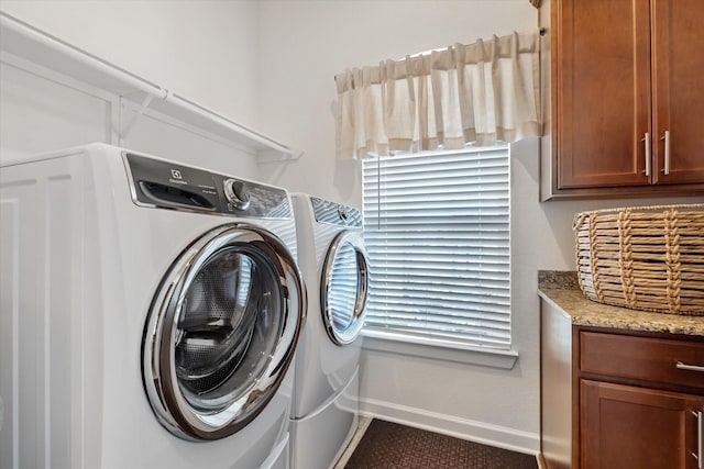 laundry room featuring independent washer and dryer, cabinet space, and baseboards