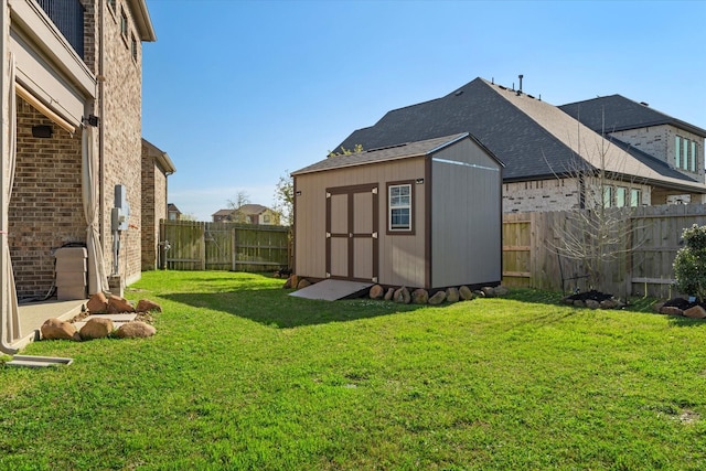 view of yard featuring a storage unit, a fenced backyard, and an outbuilding