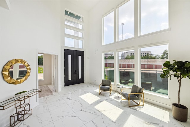 4670 Cedar St, Bellaire, TX 77401 - foyer with marble look tile flooring, healthy amount of natural light, a towering ceiling, and french doors