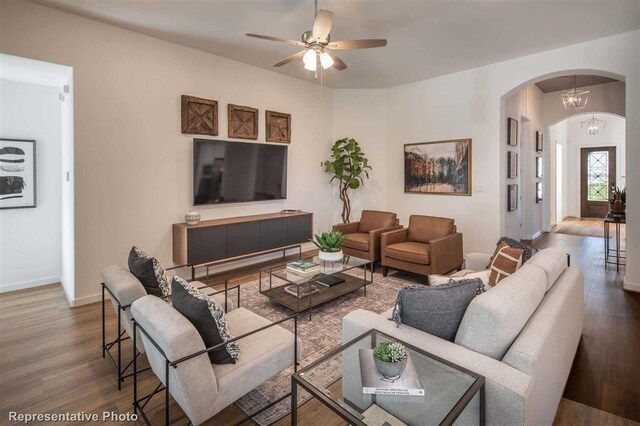 living room with arched walkways, ceiling fan, baseboards, and wood finished floors