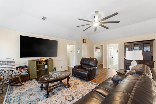 living area with visible vents, baseboards, wood finished floors, a ceiling fan, and vaulted ceiling