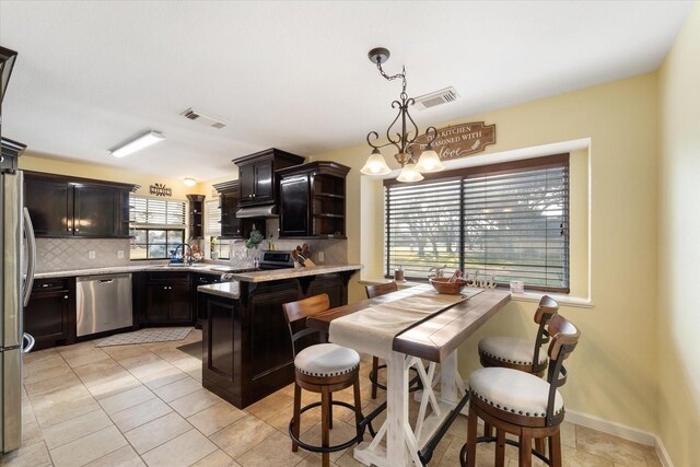 kitchen featuring light countertops, a sink, backsplash, appliances with stainless steel finishes, and visible vents