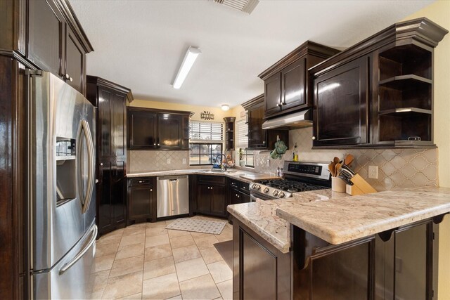 kitchen with dark brown cabinets, a peninsula, a sink, and stainless steel appliances
