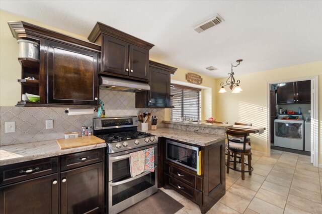 kitchen featuring a peninsula, under cabinet range hood, stainless steel appliances, independent washer and dryer, and visible vents