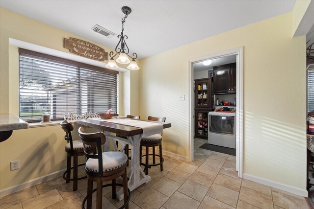 dining space featuring baseboards, light tile patterned floors, visible vents, and washer / dryer