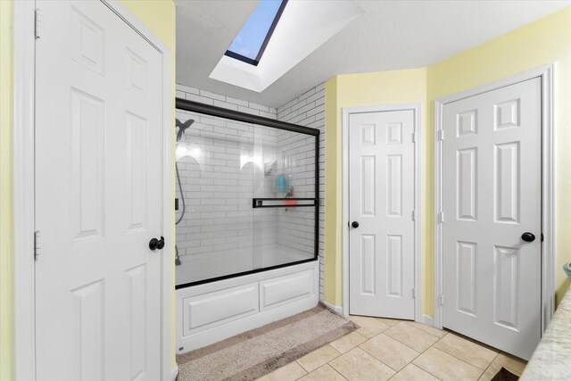 full bath with tile patterned floors, bath / shower combo with glass door, and a skylight