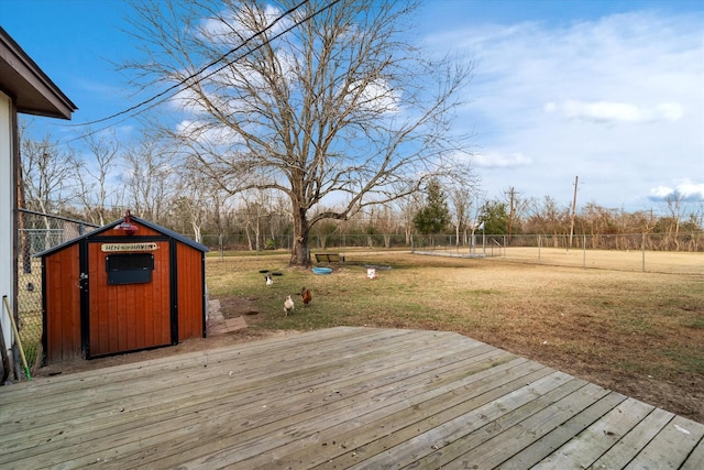 wooden deck with a yard, an outbuilding, a shed, and fence