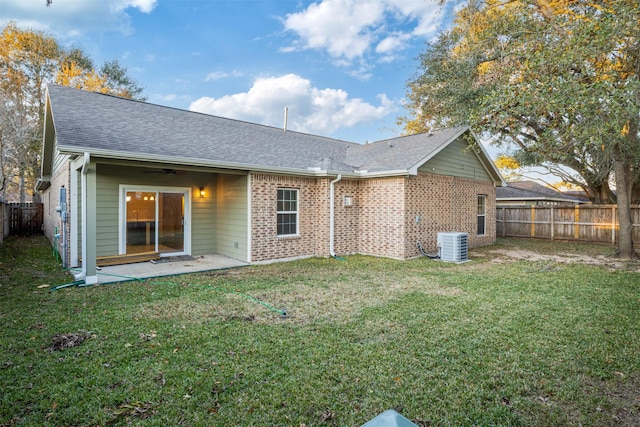 rear view of property with roof with shingles, central air condition unit, a fenced backyard, ceiling fan, and a yard