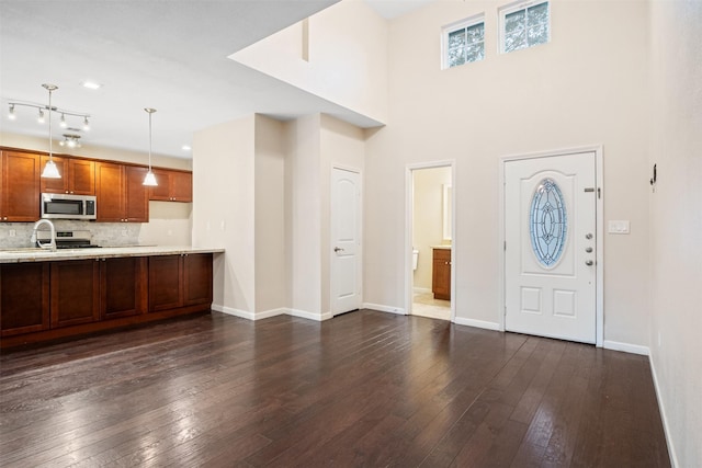 foyer entrance featuring dark wood-style floors, a towering ceiling, and baseboards
