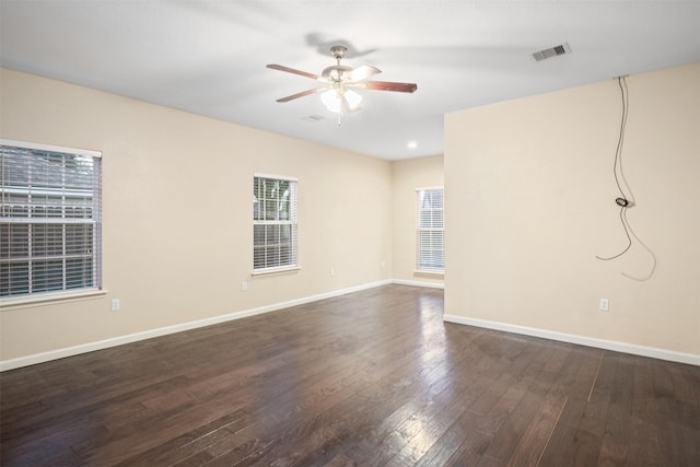 unfurnished room featuring dark wood-style floors, visible vents, baseboards, and a ceiling fan