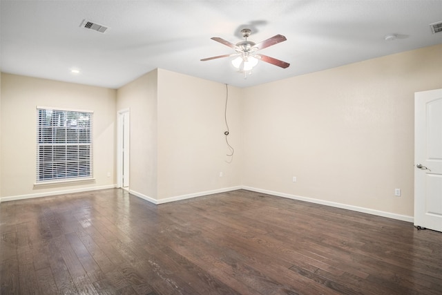 empty room featuring dark wood-type flooring, baseboards, ceiling fan, and visible vents