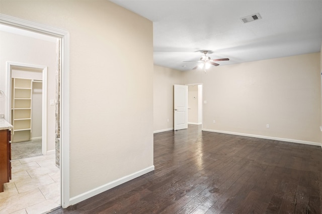 spare room featuring baseboards, visible vents, a ceiling fan, and wood finished floors